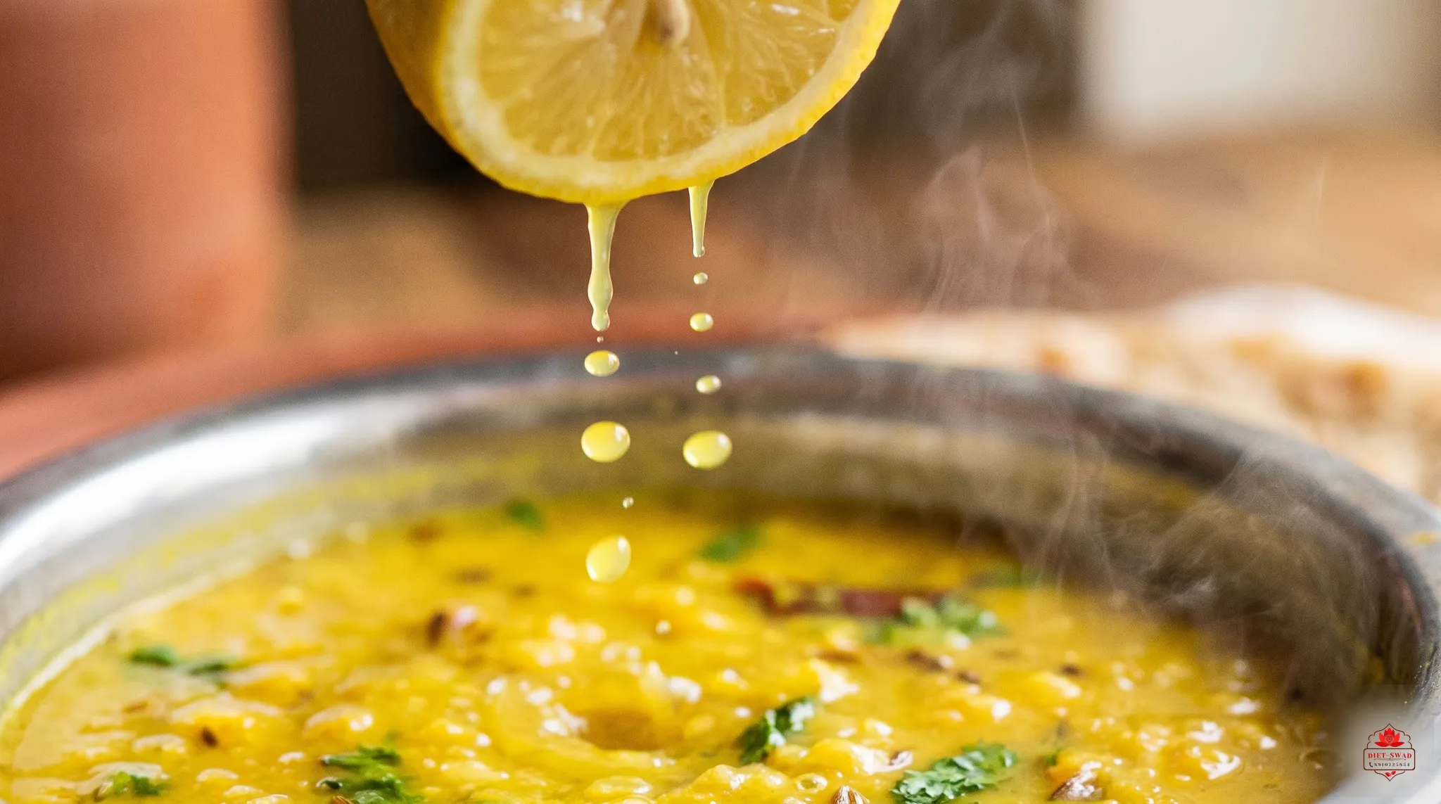 Lemon juice being squeezed over a steaming bowl of yellow dal